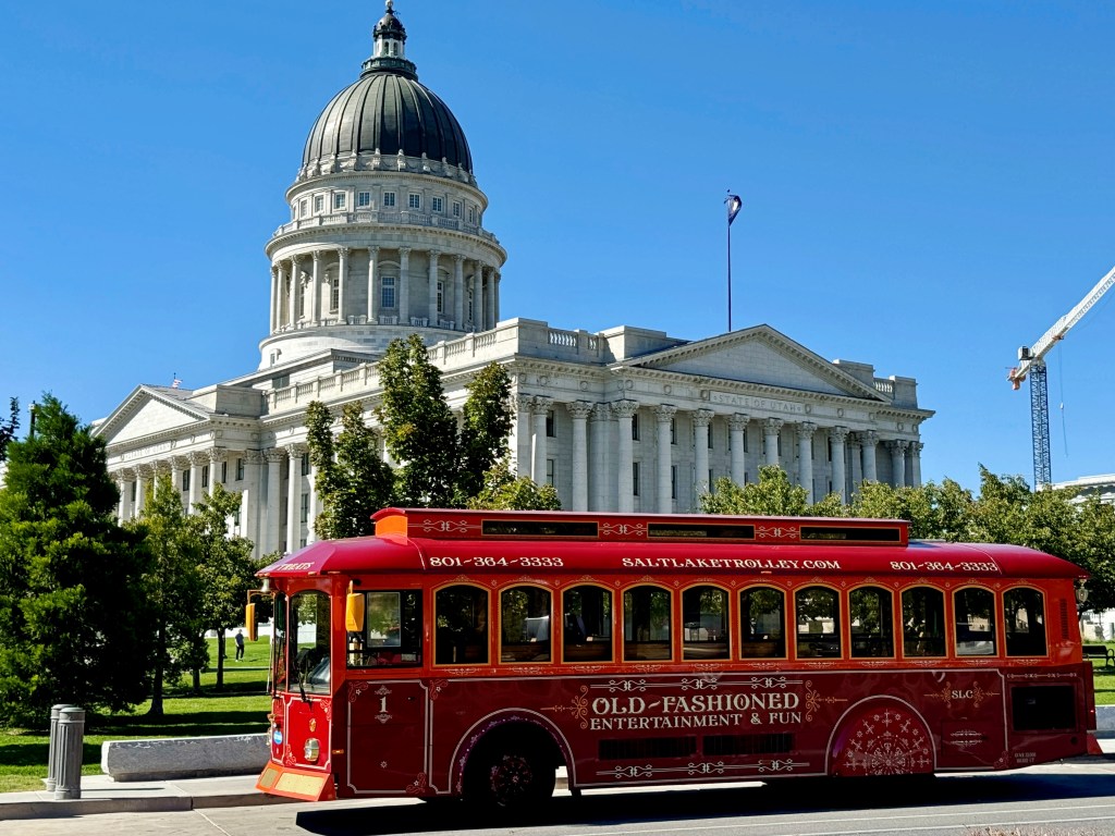 Red sightseeing trolley passing the Utah State Capitol building in Salt Lake City