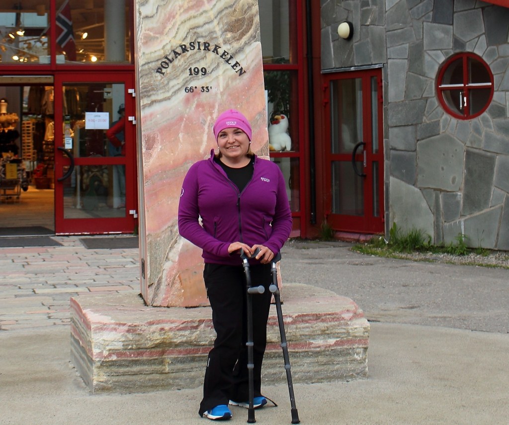Adele Heidenreich standing with crutches at the Arctic Circle monument in Norway