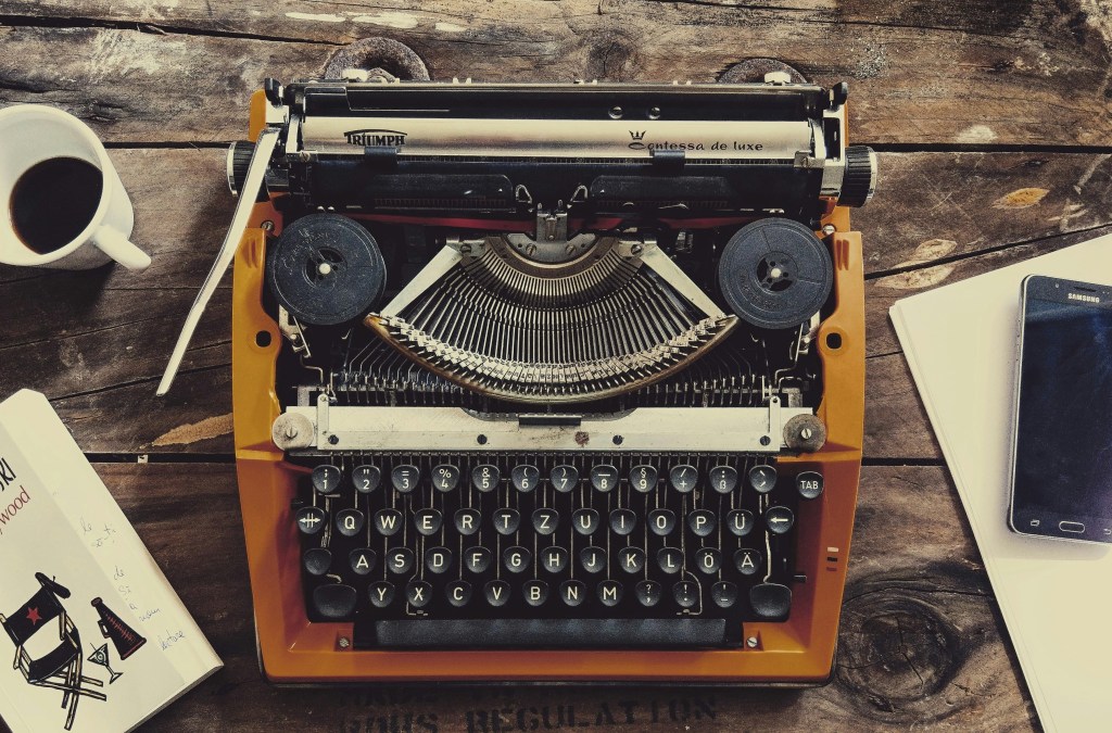 Vintage typewriter on a wooden desk with scattered papers.