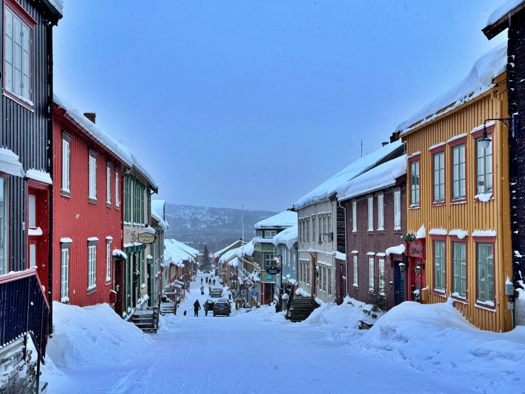 Snow-covered street in Røros with colorful shops and buildings 