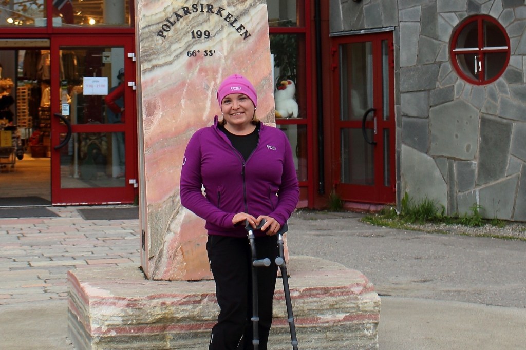 Adele Heidenreich standing with crutches at the Arctic Circle monument in Norway